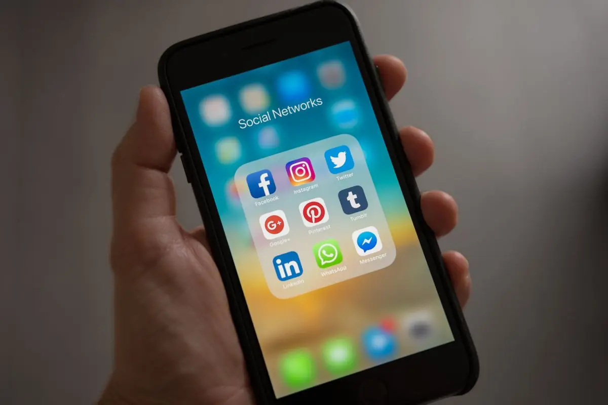 Mão segurando celular com o WhatsApp e outros aplicativos, canal onde chegam os leads da PME